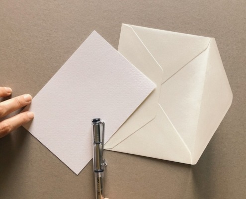 a person cutting out a piece of paper with a pen